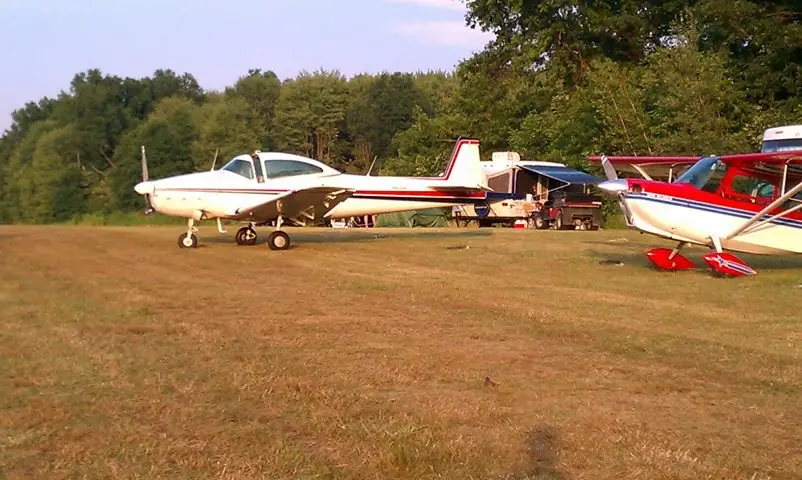 General aviation airplanes parked on a grass field in evening light